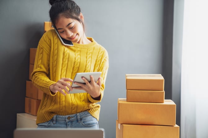 Mercado Pago: mulher vestindo suéter amarelo com calça jeans enquanto fala no telefone para identificar a melhor plataforma única de pagamentos online