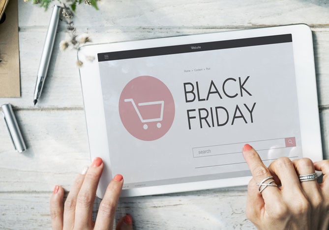 Mercado Pago: tablet em cima da mesa com a tela ligada em um site anunciando a Black Friday e mãos de uma mulher fazendo a navegação