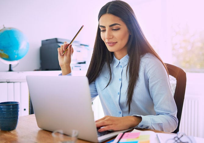 Mercado Pago: imagem de uma mulher em sua mesa de trabalho, estudando mais sobre como fazer dropshipping no Mercado Livre por meio de um notebook que está à sua frente.