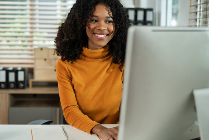Mercado Pago: mulher em frente a um computador em um escritório fazendo a gestão de clientes inadimplentes.