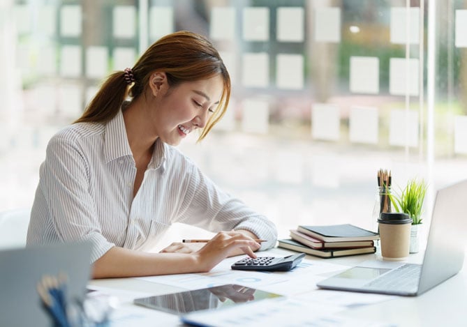Mulher vestindo uma camisa branca sentada e mexendo na calculadora para identificar as melhores oportunidades de crédito empresarial Mercado Pago