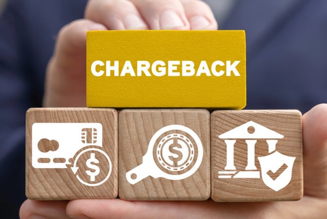 Mercado Pago: mãos segurando bloquinhos de madeira com símbolos financeiros e um deles é azul, onde está escrito “chargebacks”.