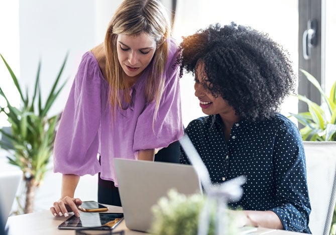 Mercado Pago - Duas mulheres conversando no trabalho sobre planejamento financeiro da empresa