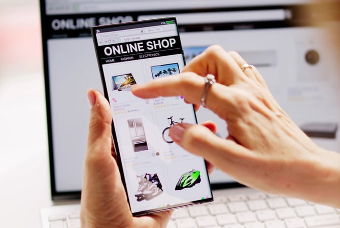 Mercado Pago: mãos mexendo em um celular e, ao fundo, há um computador, ambos os dispositivos estão com a mesma página aberta, mostrando que se trata de um site responsivo