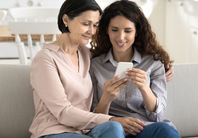 Mercado Pago: Imagem representando o Dia das Mães, com mãe e filha sorrindo juntas enquanto olham para um smartphone, em um ambiente aconchegante e familiar.