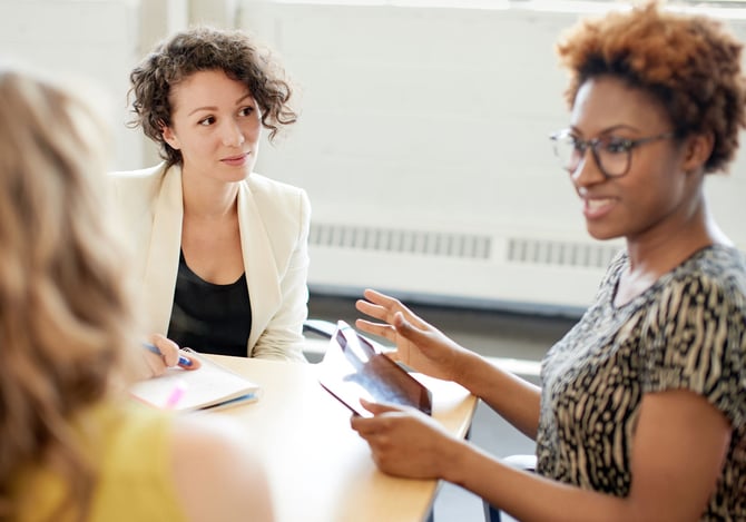 Três mulheres conversando em um ambiente profissional