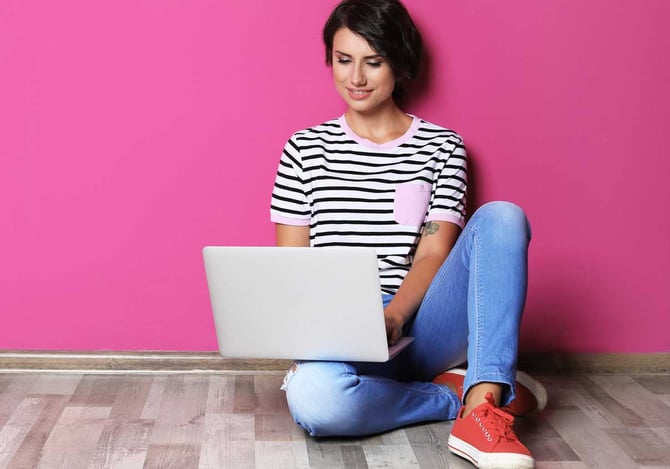 Mulher sentada no chão com um notebook no colo