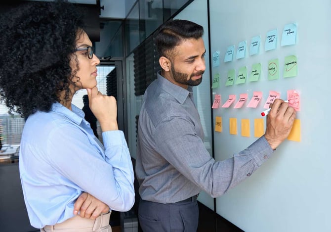 Homem e mulher fazendo a gestão estratégica da empresa com post it