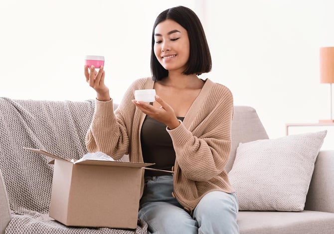 Mulher segurando produtos de beleza que recebeu em uma caixa