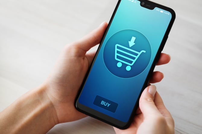 Pessoa segurando um smartphone com tela aberta em um carrinho de compra online sugerindo a integração com o checkout Pro do Mercado Pago