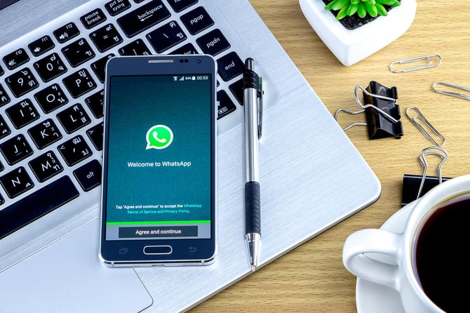  Mercado Pago: Imagem ilustrativa de celular com símbolo da conta comercial no WhatsApp com uma caneta ao lado e em cima do notebook
