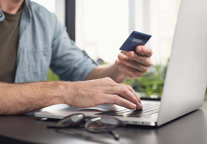 Pessoa segurando cartão de crédito enquanto digita informações no laptop para conhecer mais informações sobre o Checkout Bricks do Mercado Pago