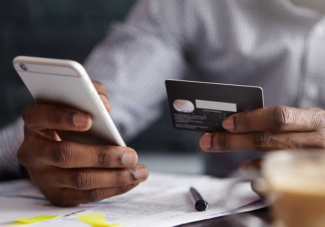 Homem mexendo no celular enquanto analisa o cartão do Mercado Pago Benefícios