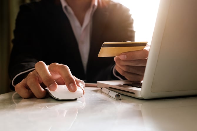 Pessoa mexendo no laptop para digitar o número do cartão Mercado Pago para efetuar uma compra e permitir que a empresa venda hoje e receba no mesmo dia