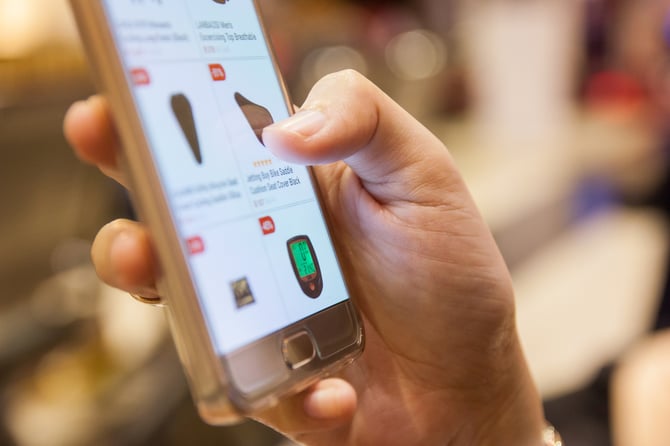 Mão de uma pessoa segurando e mexendo em um smartphone aberto em um e-commerce representando a experiência de compra online Mercado Pago