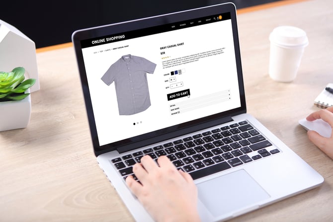 Mão de uma pessoa mexendo no laptop com a página aberta em uma loja online para vender na internet uma camiseta com auxílio do checkout Mercado Pago