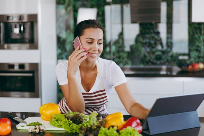 Mercado Pago: Empresária em cozinha, com celular e tablet na mão fazendo o comércio contextual 