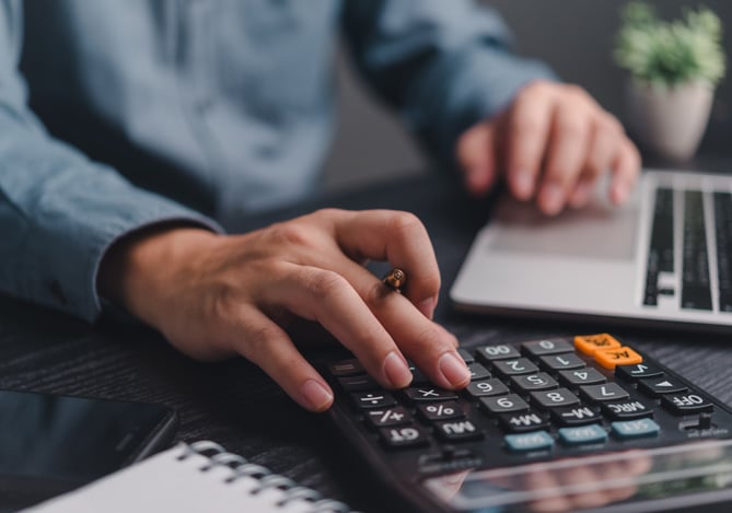 Mercado Pago: mãos de um homem com camisa social mexendo em uma calculadora e um notebook para estudar a solicitação de capital de terceiros para a empresa.