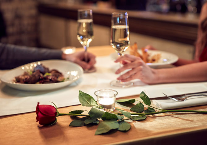 Mercado Pago: casal sentado em uma mesa de restaurante enquanto aproveitam uma das melhores ideias para o Dia dos Namorados.