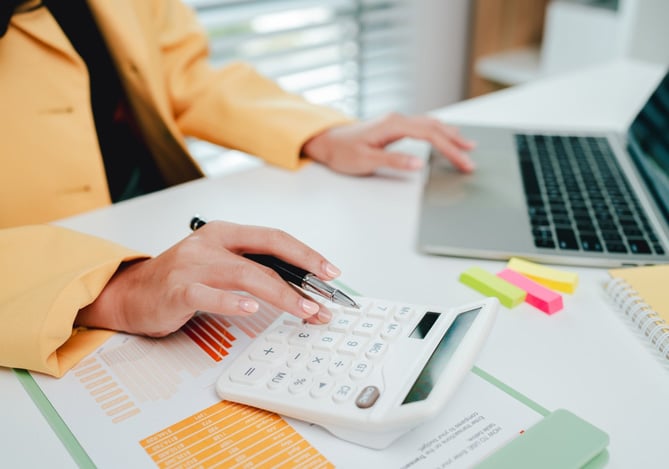 Mercado Pago: mulher mexendo em notebook e calculadora para entender o prazo médio de recebimento da sua empresa.