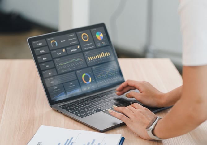 Mercado Pago: pessoa analisando gráficos em um notebook com dashboards de desempenho, representando a visualização de um relatório financeiro em ambiente profissional.