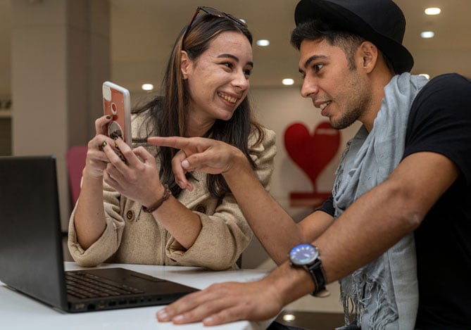 Mercado Pago: Homem e mulher conversando e olhando no smartphone como funciona a taxa de conversão da empresa para melhor performance
