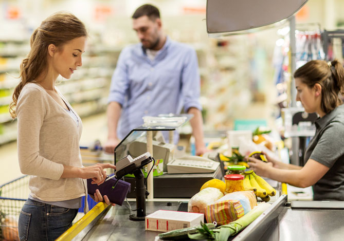Mulher realizando compras em um caixa de supermercado utilizando a Maquininha Point Mercado Pago