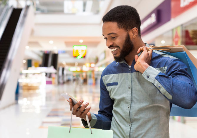 Experiência multicanais Mercado Pago: consumidor realizando compras no shopping e olhando para o celular