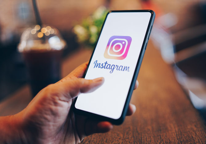 Mercado Pago: Mão de empresário segurando celular e conferindo as novidades do Instagram