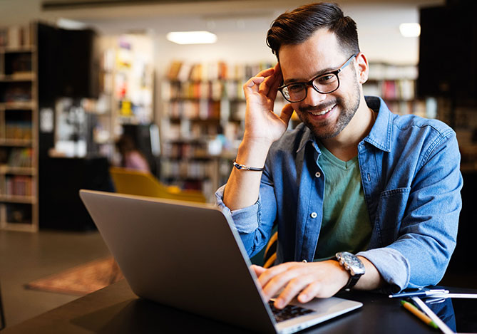 Homem usando óculos e camisa azul, com notebook, acessando uma plataforma de vendas online do Mercado Pago