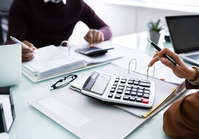 Mercado Pago: Empresário em mesa de escritório com calculadora e cadernos definindo o regime de tributação de sua empresa