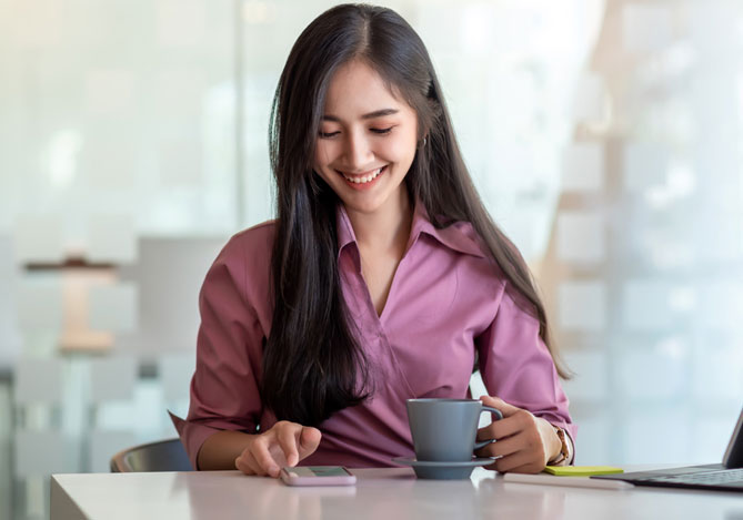 Mulher feliz tomando café e usando o Mercado Pago para aumentar a rentabilidade da sua empresa