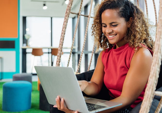 Empresária de e-commerce vestindo blusa rosa com notebook aberto na tela Mercado Pago, em sua empresa