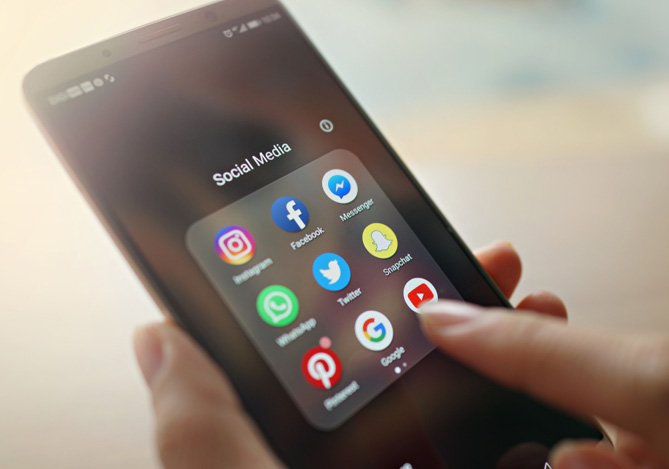 Empresária segurando celular com aplicativos de redes sociais para vender na internet